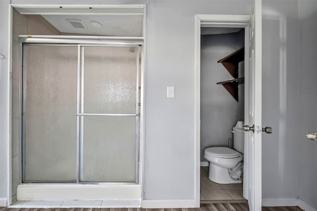 bathroom with toilet, hardwood / wood-style floors, and a shower with shower door