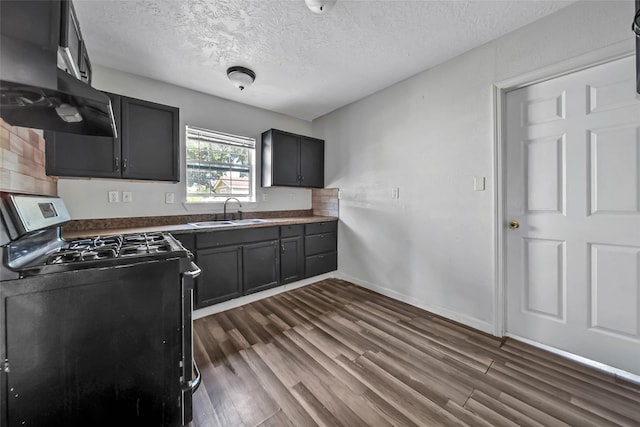 kitchen featuring a textured ceiling, black range with gas stovetop, dark wood-type flooring, range hood, and sink