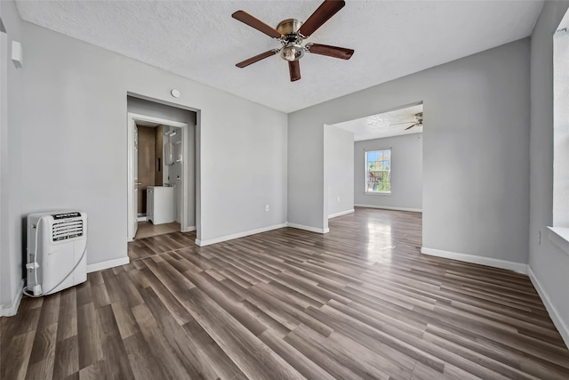 unfurnished living room with a textured ceiling, ceiling fan, heating unit, and dark hardwood / wood-style flooring