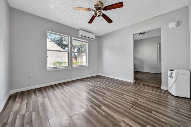 empty room featuring ceiling fan, an AC wall unit, a textured ceiling, and dark hardwood / wood-style floors