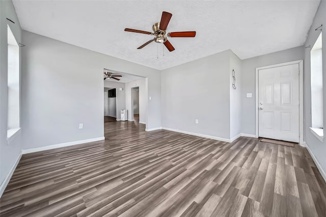 unfurnished living room featuring ceiling fan, a textured ceiling, and dark hardwood / wood-style flooring