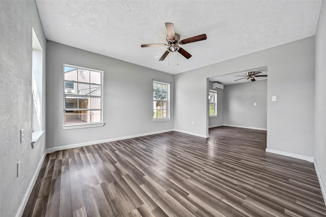 unfurnished room featuring ceiling fan, a textured ceiling, a wealth of natural light, and dark hardwood / wood-style floors