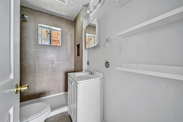 full bathroom with vanity, tiled shower / bath, a textured ceiling, and toilet