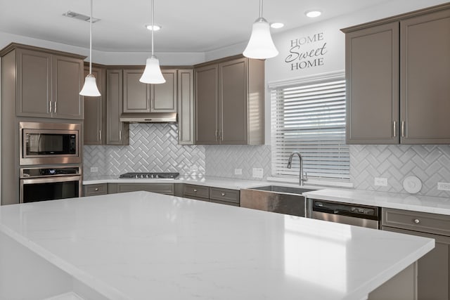 kitchen featuring light stone countertops, backsplash, appliances with stainless steel finishes, and hanging light fixtures