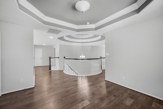 unfurnished room featuring dark wood-type flooring, a notable chandelier, and a tray ceiling