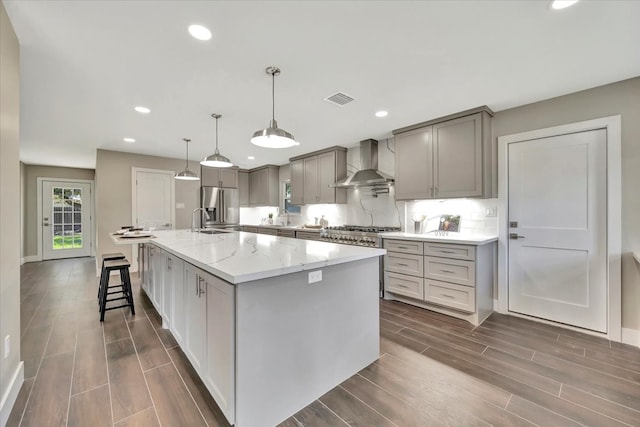 kitchen featuring a spacious island, light stone counters, wall chimney exhaust hood, and dark hardwood / wood-style floors