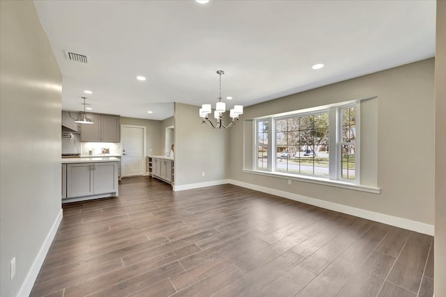 unfurnished living room featuring a notable chandelier and dark hardwood / wood-style floors