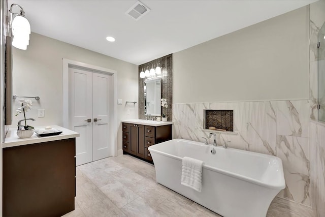 bathroom featuring a bathing tub, vanity, and tile walls