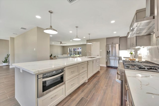 kitchen with sink, a large island, decorative light fixtures, dark wood-type flooring, and high end appliances