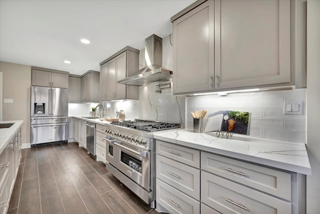 kitchen with wall chimney range hood, dark hardwood / wood-style flooring, backsplash, sink, and high end appliances