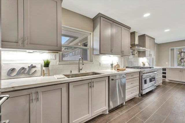 kitchen with gray cabinets, sink, appliances with stainless steel finishes, and wall chimney range hood