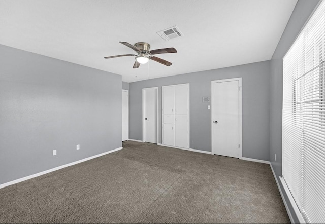 unfurnished bedroom featuring a ceiling fan, baseboards, visible vents, multiple closets, and carpet