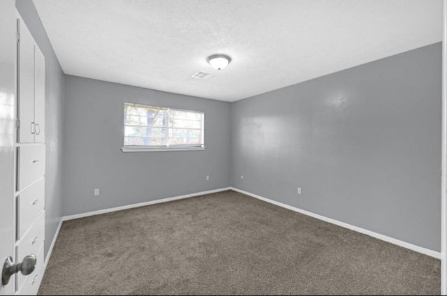 unfurnished room featuring carpet flooring, visible vents, and baseboards