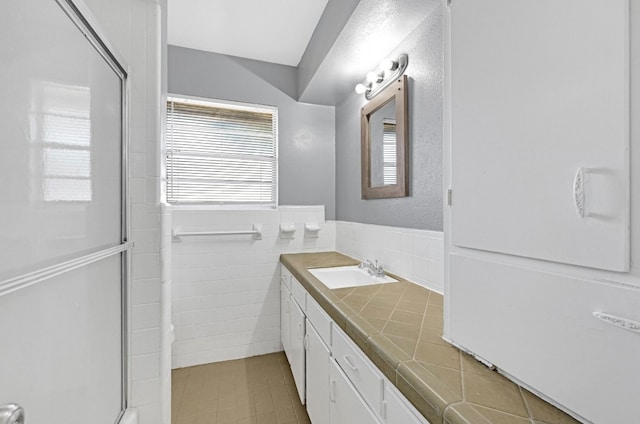 bathroom featuring vanity, walk in shower, tile walls, and tile patterned flooring