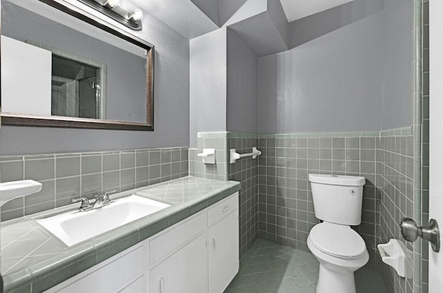 bathroom with a wainscoted wall, vanity, toilet, and tile walls