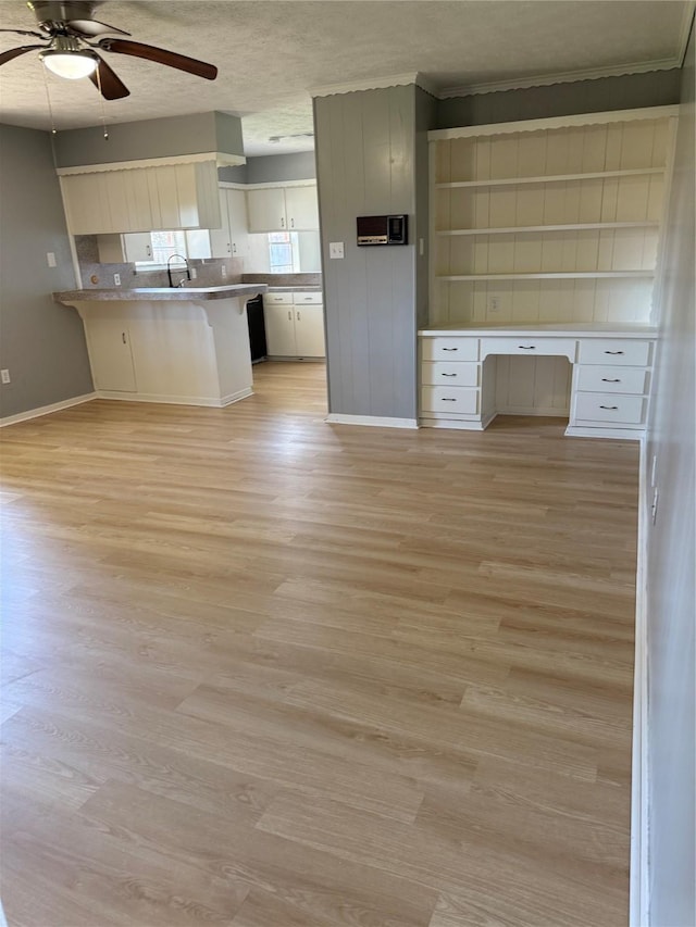 kitchen featuring light wood-type flooring, built in desk, a peninsula, and a breakfast bar area