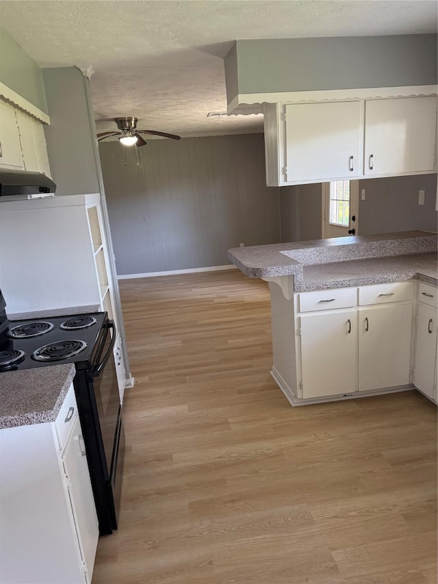 kitchen with light wood-style flooring, black electric range, white cabinetry, and a peninsula