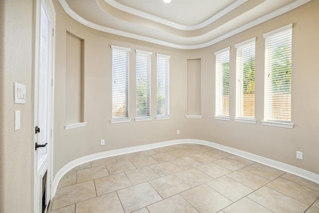 empty room with crown molding, light tile patterned floors, and a raised ceiling