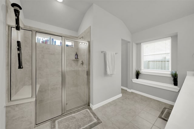 bathroom with a shower with door, tile patterned floors, and lofted ceiling