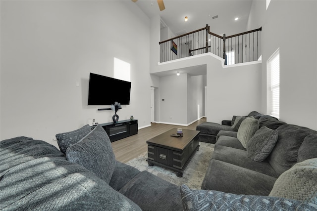 living room with a high ceiling, wood-type flooring, and ceiling fan