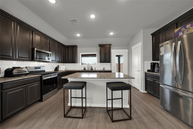 kitchen featuring a kitchen island, a kitchen breakfast bar, stainless steel appliances, sink, and light wood-type flooring