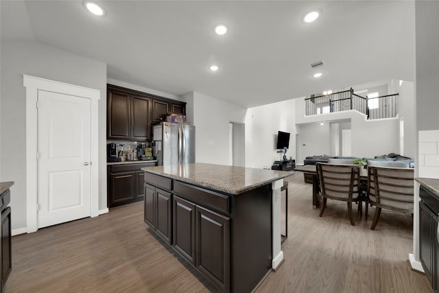 kitchen with stainless steel fridge, a center island, dark brown cabinets, and dark hardwood / wood-style floors