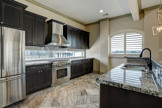 kitchen with light stone countertops, sink, stainless steel appliances, wall chimney exhaust hood, and ornamental molding