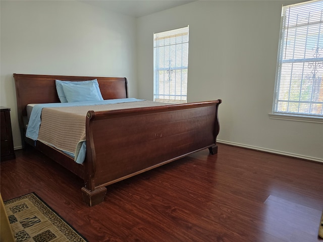 bedroom with multiple windows and dark hardwood / wood-style floors