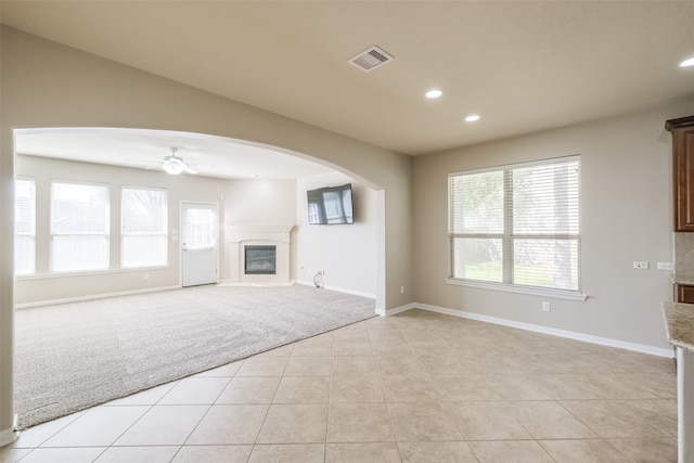 unfurnished living room featuring light carpet and ceiling fan