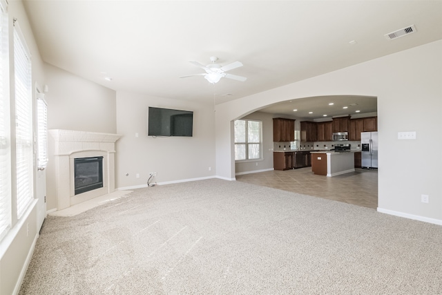 unfurnished living room featuring light carpet and ceiling fan