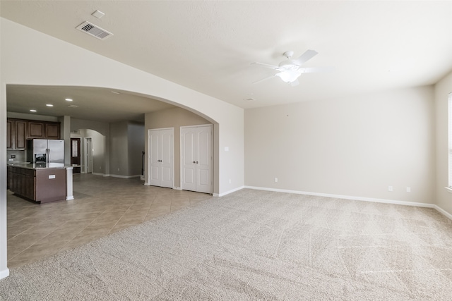 unfurnished living room with light carpet and ceiling fan