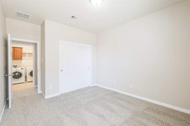 unfurnished bedroom with light carpet, a closet, and washing machine and clothes dryer