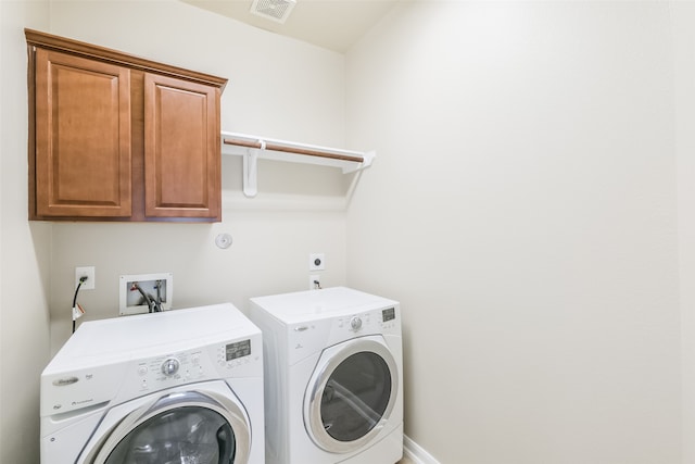 clothes washing area with washer and dryer and cabinets