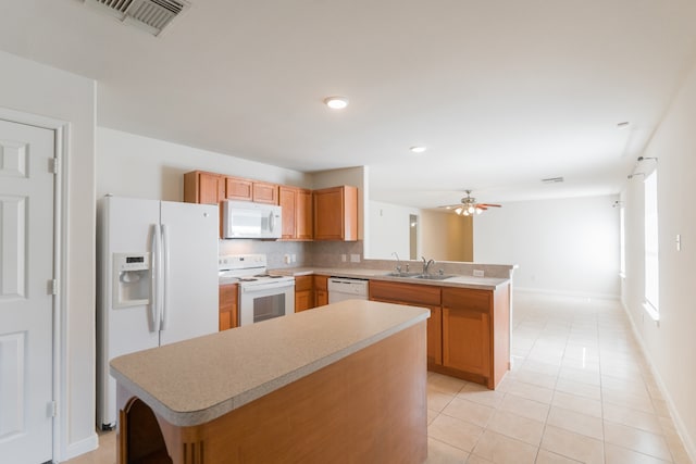 kitchen with white appliances, a kitchen island, kitchen peninsula, decorative backsplash, and light tile patterned floors