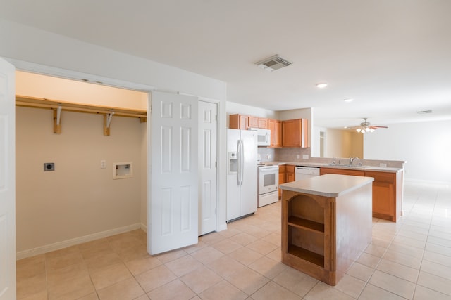 kitchen with light tile patterned flooring, kitchen peninsula, sink, and white appliances