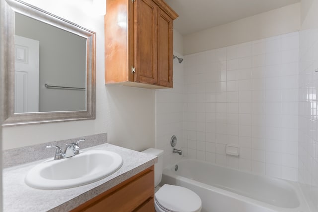 full bathroom featuring tiled shower / bath, vanity, and toilet