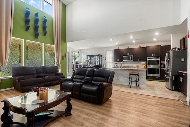 living room featuring light hardwood / wood-style floors, a towering ceiling, and sink