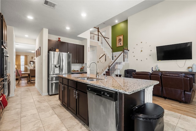 kitchen featuring dark brown cabinets, a center island with sink, appliances with stainless steel finishes, light hardwood / wood-style flooring, and sink