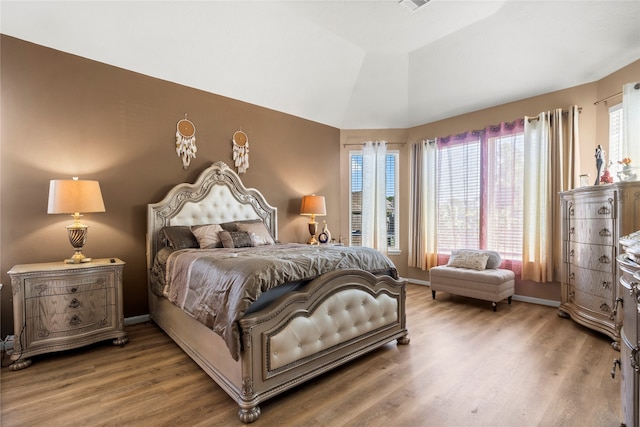 bedroom featuring multiple windows, wood-type flooring, and vaulted ceiling