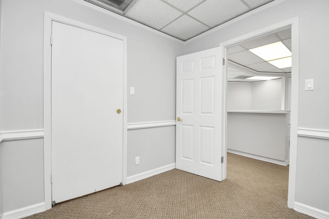 interior space with a closet, a paneled ceiling, and light colored carpet