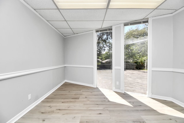 empty room featuring a paneled ceiling and light wood-type flooring