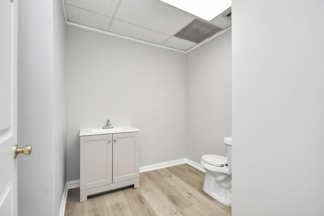 bathroom featuring toilet, a drop ceiling, vanity, and wood-type flooring