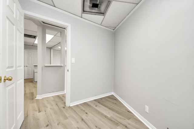 empty room featuring crown molding, light hardwood / wood-style flooring, and a paneled ceiling