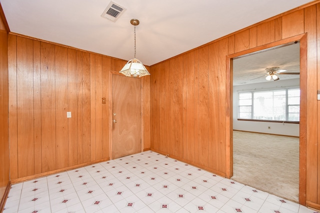 empty room with ceiling fan, light carpet, and wooden walls