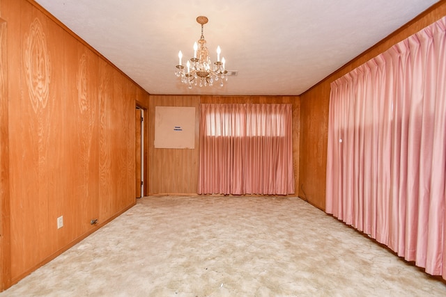 unfurnished room with an inviting chandelier and wooden walls