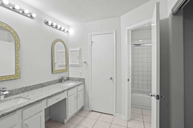 bathroom featuring vanity, tiled shower / bath combo, a textured ceiling, and tile patterned flooring