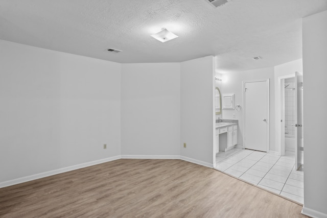 unfurnished room with light hardwood / wood-style flooring and a textured ceiling