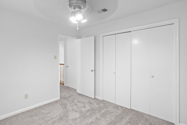 unfurnished bedroom with a closet, ceiling fan, and light colored carpet