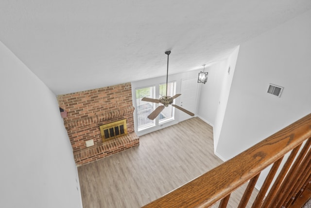 living room with light hardwood / wood-style flooring, a fireplace, and ceiling fan with notable chandelier