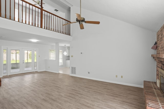 unfurnished living room featuring wood-type flooring, a fireplace, french doors, ceiling fan, and high vaulted ceiling